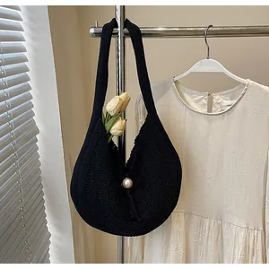 Macro view of black knit tote featuring a large pearl button and vertical texture detail