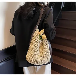 Close-up of woven straw shoulder bag with dark brown leather strap and tulip decor