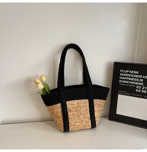 Detail of summer straw tote bag with black strap accents and yellow tulip decor