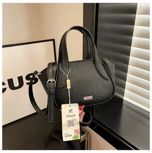Makro-Detail der schwarzen Lederhandtasche mit Litschi-Maserung und edlem Metalllogo