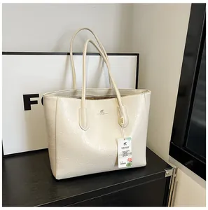 Close-up of beige leather tote bag featuring a kangaroo logo and textured leather finish