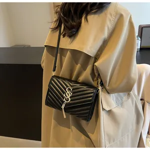 Details einer schwarzen gesteppten Umhängetasche mit Goldlogo und Metallquaste