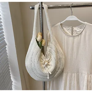 Detail of hand-woven off-white shoulder bag with large pearl button and knit texture