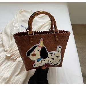 Detail of woven tote bag with natural bamboo handles and cartoon puppy patch embroidery