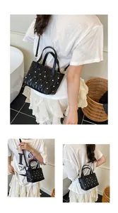 Close-up of black quilted leather crossbody bag with silver rivet details and chain strap