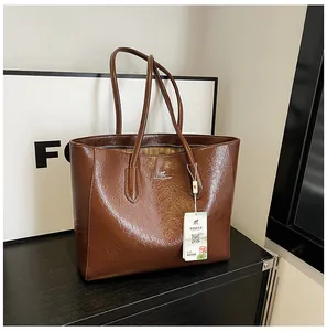 Detail of glossy brown pleated tote bag with kangaroo logo and secure zipper closure