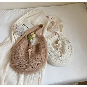 Detail view of woven knit shoulder bags with pearl buttons on white fabric background