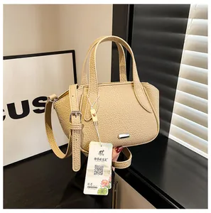 Detail einer beige Handtasche aus genarbtem Leder mit Metallschnalle und verstellbarem Gurt