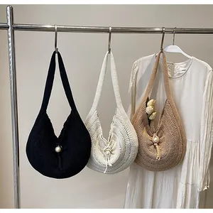 Detail of woven hobo bags in khaki and cream featuring a large pearl clasp closure