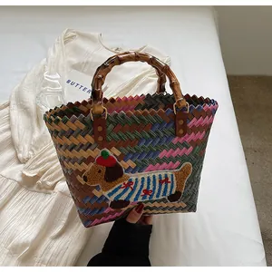Close-up of a colorful woven tote bag featuring a cute dachshund patch and bamboo handles