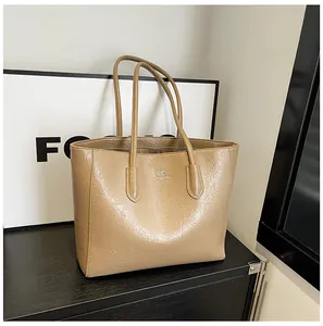 Detail of khaki tote bag with crinkled glossy leather texture and metal logo