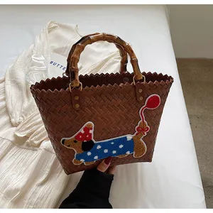 Detail of hand-woven tote bag with bamboo handles and cute dachshund embroidery