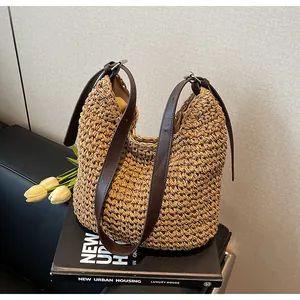 Detail of woven straw hobo bag with adjustable leather strap and silver buckle