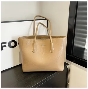 Detail of camel tote bag with pleated texture and silver metallic logo on front
