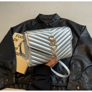 Nahaufnahme der silbernen Stepptasche mit goldenem Logo und Quasten-Detail für Damen