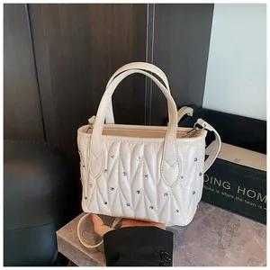 Detail of cream quilted leather handbag featuring sparkling rhinestones and double handles