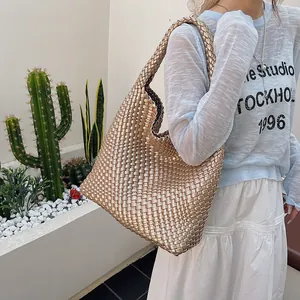 Sac fourre-tout tissé couleur champagne doré style hobo porté par un mannequin en extérieur