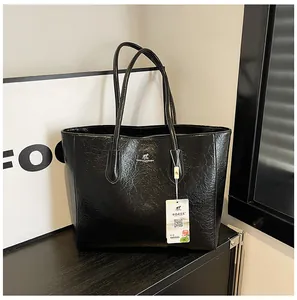 Detailed view of black oil wax leather tote bag with silver metal kangaroo logo badge