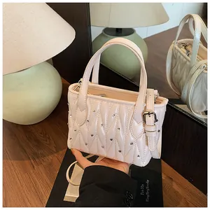 Detail of cream quilted leather mini bag with sparkling rhinestones and heart stitching