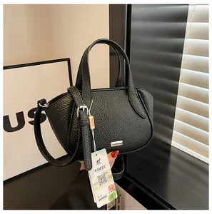 Seitenansicht der schwarzen Handtasche aus Kieselleder mit Metalllogo und Gurt