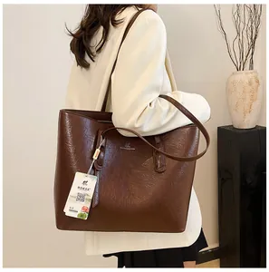Detailansicht der karamellbraunen Leder-Shopper mit Logo-Prägung und langem Schultergurt
