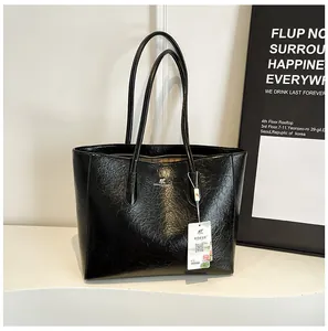 Close-up of black oil wax leather tote bag with silver logo for office commute