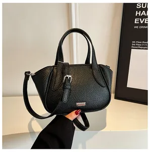 Detailansicht der schwarzen Handtasche aus Narbenleder mit Silberverschluss und Gurt