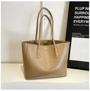 Detail of khaki tote bag showing oil wax pleated texture and silver logo on the side
