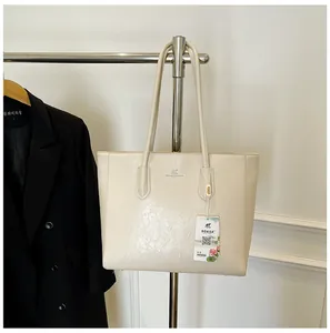 Close-up of cream tote bag featuring textured faux leather and a silver kangaroo logo