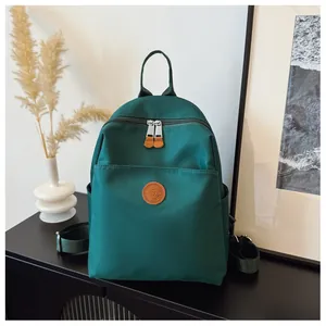 Detailed view of dark green nylon backpack with leather logo on a black side cabinet