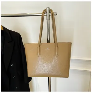 Detail of camel oil-wax tote bag with kangaroo logo hanging on a metal display rack