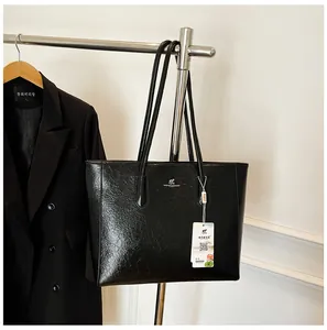 Detail of a large black leather tote bag with a kangaroo logo on a display hanger