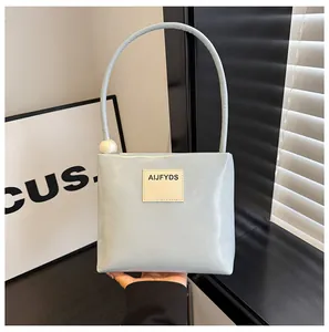 Dettaglio borsa a mano in pelle PU azzurra con manico di perla e toppa con logo quadrato