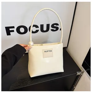 Dettaglio borsa a mano bianco crema con perla decorativa ed etichetta logo AIJFYDS