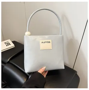Dettaglio della borsa azzurra con manico a perla e toppa con logo sul davanti