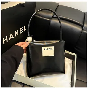 Dettaglio di borsa nera lucida con manico in perla grande ed etichetta in pelle AIJFYDS