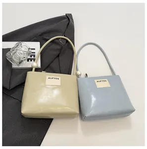 Dettaglio di borsa a mano minimalista in pelle con perla grande e patch logo rettangolare
