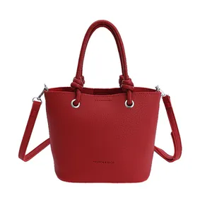 Chic red litchi texture bucket bag with knotted handles and slender shoulder strap