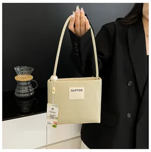 Dettaglio della borsa tote in pelle beige con perla grande e patch con lettere sulla tracolla
