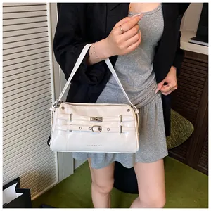 Detail einer cremeweißen glänzenden PU-Achseltasche mit Zierriemen und Metallschnallen