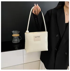 Dettaglio della borsa beige minimalista con grande perla e logo su pelle pregiata