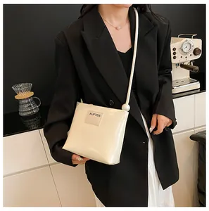 Dettaglio borsa a tracolla crema con elegante perla decorativa sulla tracolla