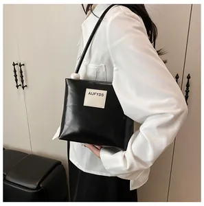 Dettaglio borsa nera in ecopelle lucida con perla decorativa e patch con logo