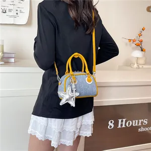 Mini denim crossbody bag with yellow leather trim and a star pendant accessory