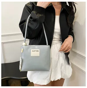 Dettaglio della borsa azzurra in pelle con decorazione a perla e logo del marchio
