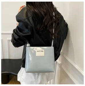 Dettaglio della borsa quadrata azzurra con una grande perla e patch del marchio