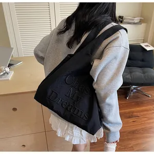 Dettaglio della borsa tote nera capiente con scritte Chase My Dreams in rilievo