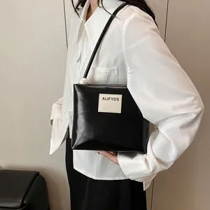 Borsa a tracolla quadrata nera minimalista con logo bianco e dettaglio di perla grande
