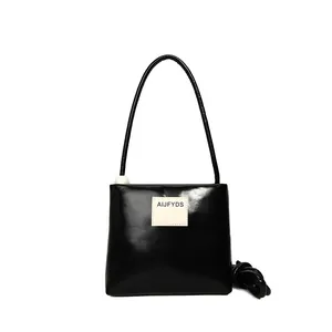 Borsa a tracolla minimalista in pelle nera con toppa logo e dettaglio di perla bianca