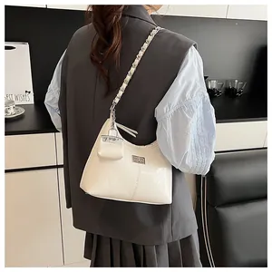 Detail van de witte Hobo-tas met zilveren draaisluiting en mini-tasvormige hanger